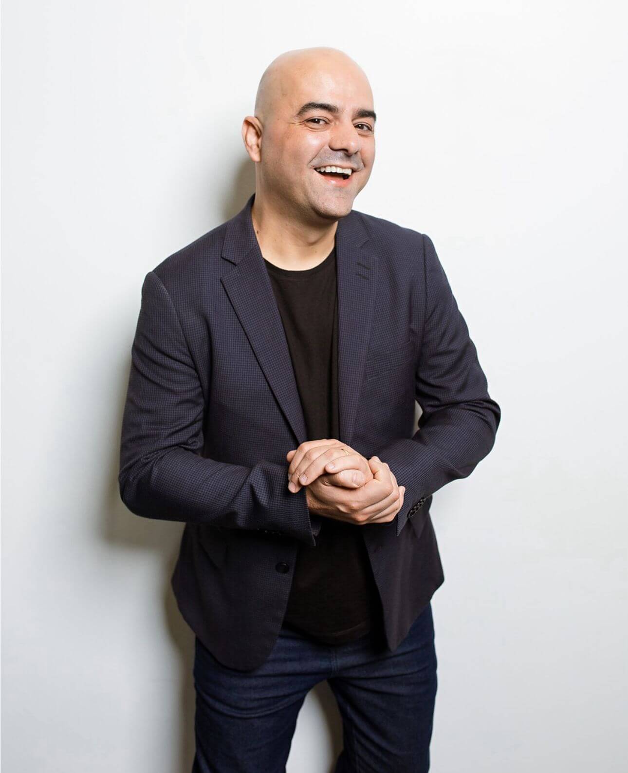 palestrante Leandro Branquinho sorrindo com as mãos juntas como se estivesse batendo palmas