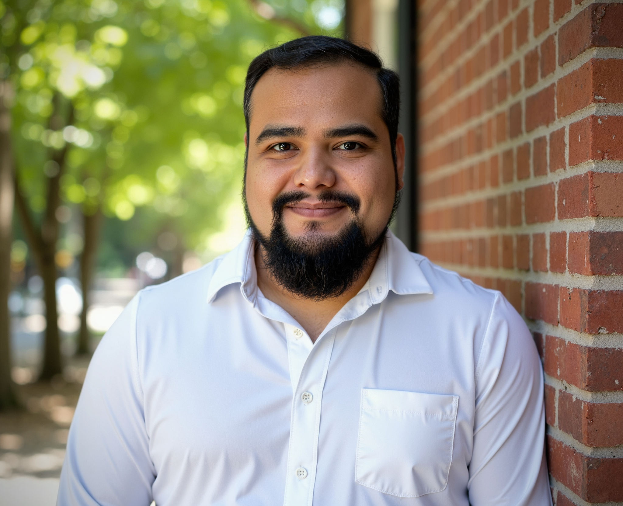 Man in white shirt standing by brick wall.